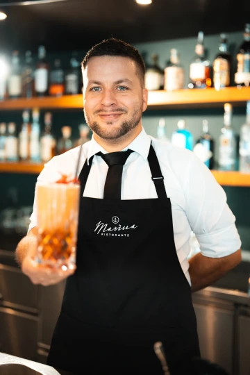 Barman Marina Ristorante s míchaným koktejlem za barem.
