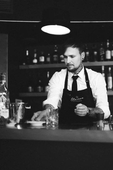 Barman Marina Ristorante připravuje koktejl za barem, černobílá fotografie.
