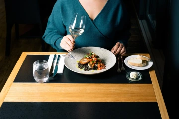 Host Marina Ristorante u oběda se sklenkou vína a moderně naservírovaným pokrmem.