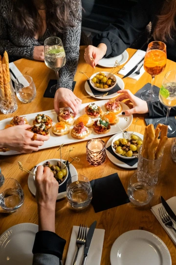Guests sharing starters and bruschetta at a communal table, seen from above.