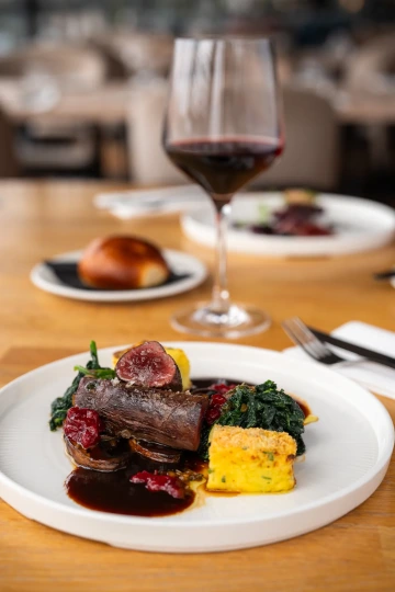 Beef with polenta and greens, served with red wine.