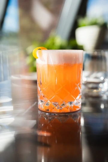 Osvěžující koktejl s citrusovou kůrou v elegantní sklenici. Dotek luxusu s ikonickým výhledem na Vltavu v Marina Ristorante.