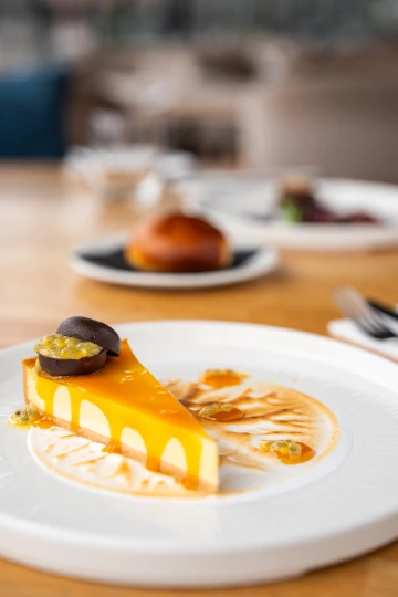 Mango cheesecake with fruit coulis on a plate.