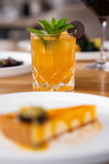 Mango cocktail with mint and a slice of cheesecake.