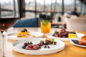 Plated meat dish with dessert and an orange cocktail in the restaurant.