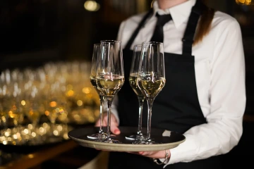 Marina Ristorante server carrying a tray of sparkling wine glasses.