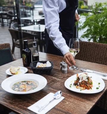 Marina Ristorante server presenting dishes on the riverside terrace.