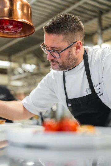 Marina Ristorante chef finishing a dish in the kitchen.