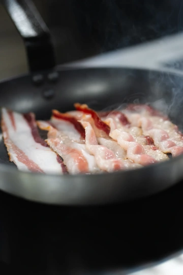 Bacon sizzling in a pan in the Marina Ristorante kitchen.