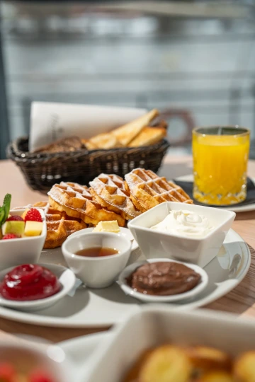 Breakfast spread with pastries, waffles, jam and coffee.
