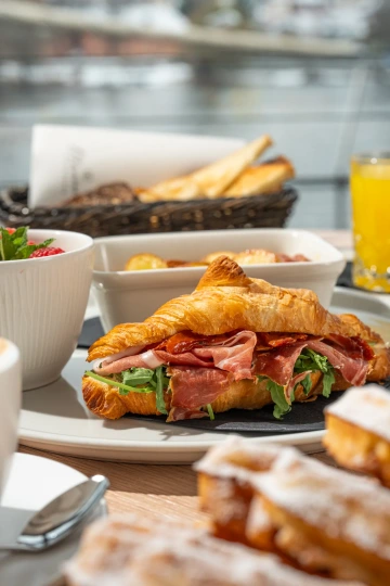 Breakfast croissant with prosciutto and fresh juice.
