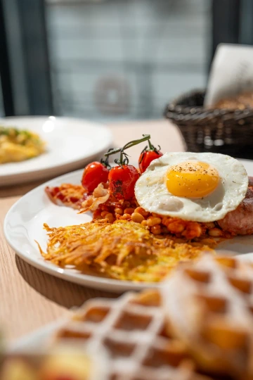 Breakfast plate with fried egg, hash and roasted tomatoes.