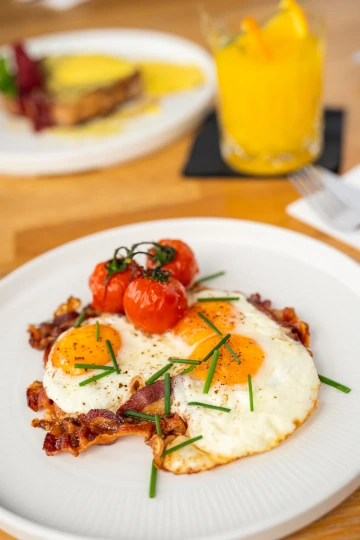 Breakfast plate with fried eggs, roasted tomatoes and fresh juice.