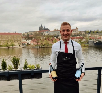 Marina Ristorante sommelier with wine bottles on the terrace overlooking Prague Castle.