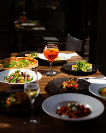 Table with salads and Aperol Spritz in the restaurant's evening ambiance.